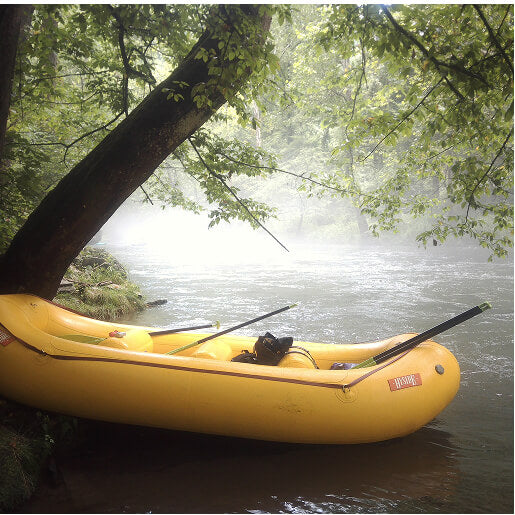 Yellow raft moored under a tree on a foggy river